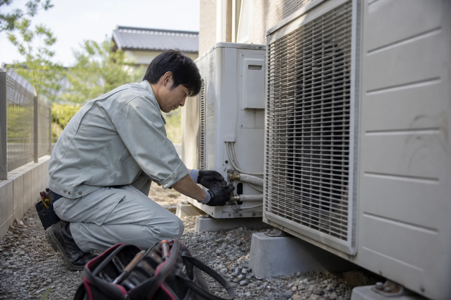 屋外の空調機器を点検する設備担当者